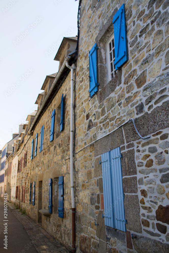 Vielle rue de maisons en pierre aux volets bleu en Bretagne