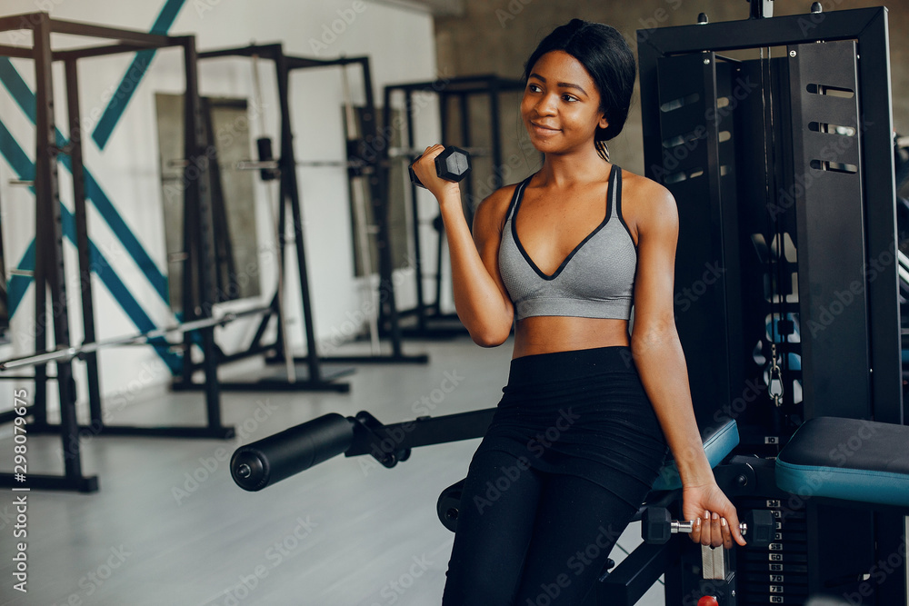 Fototapeta premium Beautiful black girl in the gym. A woman in a gray top