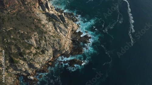 Aerial Orbit of Big Waves Crashing against Rocks in Ocean. Seascape Coastline at Sunset in Cape Town photo