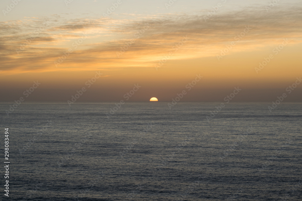 Beautiful sunset with orange colors in the sky and the sun hiding in the sea on the horizon