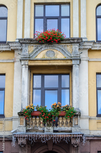 Yellow wall and stone old balcony in baroque style. Pots with flover.