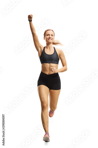 Happy young woman running towards the camera with raised arm