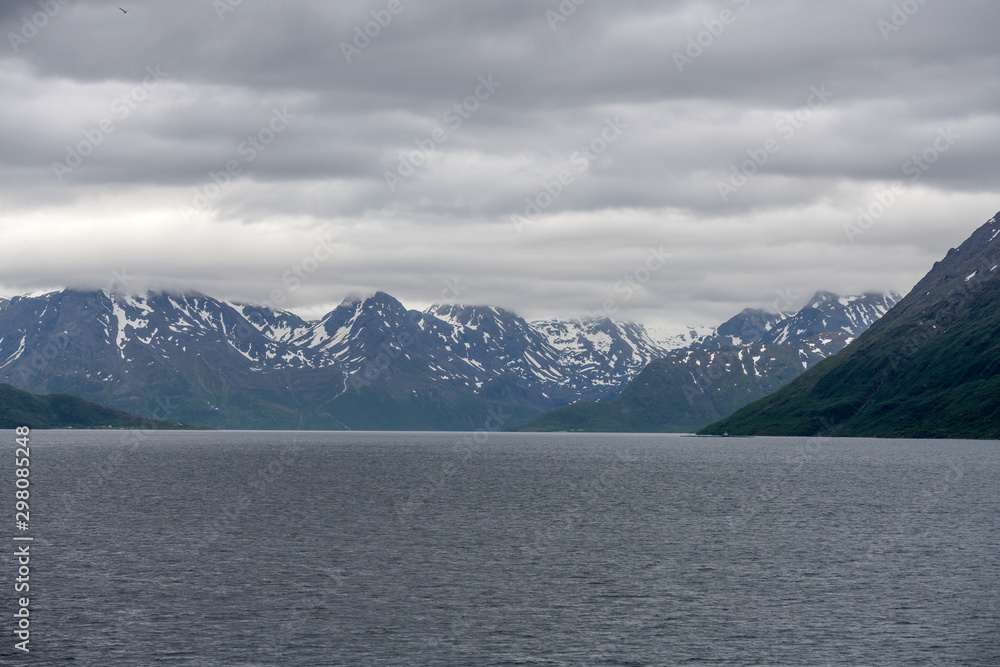 summer snow and bright clouds in northern fjord near Soroya island, Norway summer snow and bright clouds in northern fjord near Soroya island, Norway
