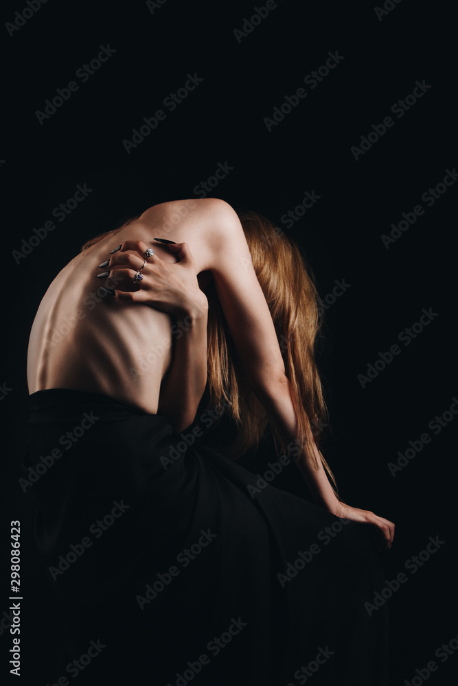 A girl with a bare back, severe thinness and protruding ribs. The concept of anorexia and bulimia, a disease of thin people. The struggle of the evil spirit in a girl, suffering and poverty.
