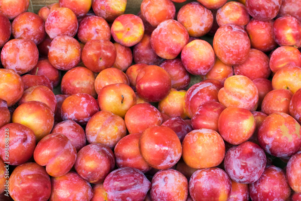 Plum background. Red fresh ripe plums placed on table in market. Organic red plums fruit in local farmers market. Plum background. Red fresh ripe plums placed on table in market. Organic red plums fruit in local farmers market.