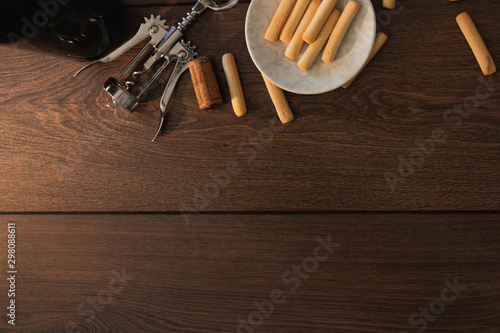 bottle of wine with corkscrew and some snack food on wooden table with copy and paste space