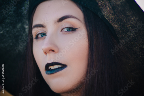 Portrait young  beautiful girl with pale skin and black lips in the form of a witch for Halloween. A model with clean skin.
