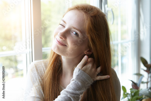 portrait of pretty young woman with red hair and freckles winking, smiling