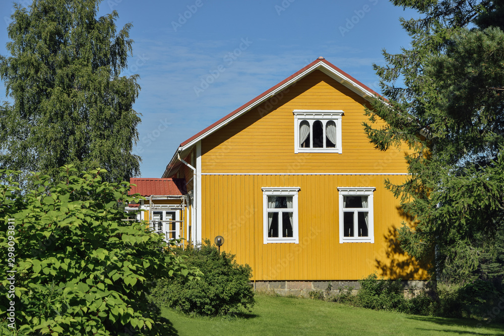 Yellow wooden finnish house in countyside at strawberry farm summer sunny day with green lawn and trees