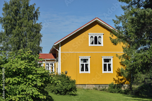 Yellow wooden finnish house in countyside at strawberry farm summer sunny day with green lawn and trees © Tatiana Parfenteva