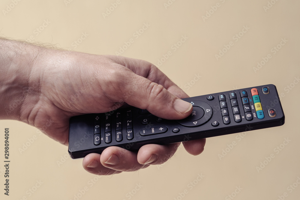 Male hand with a TV remote control close-up. The man turns on the TV Male hand with a TV remote control close-up. The man turns on the TV