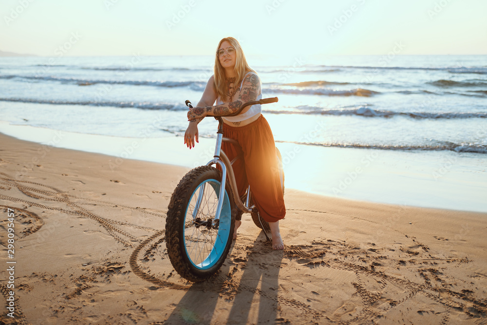 Joyful woman riding bicycle along peaceful beach Joyful woman riding bicycle along peaceful beach