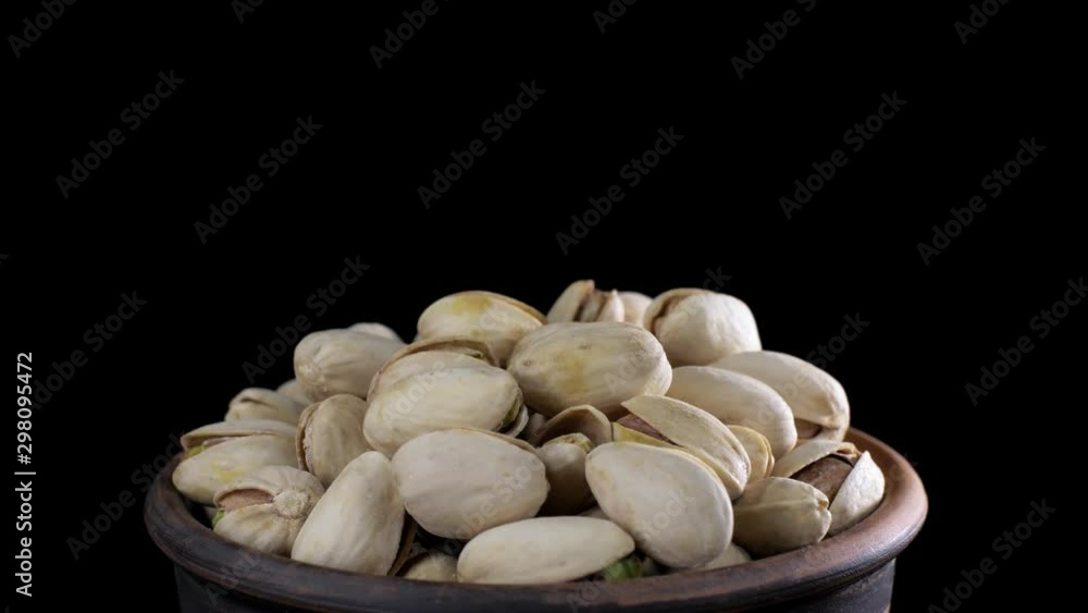 Pistachio nut with salt. Roasted pistachios rotate on a black background. Pistachios in a bowl isolated on black. Pistachio nut with salt. Roasted pistachios rotate on a black background. Pistachios in a bowl isolated on black.