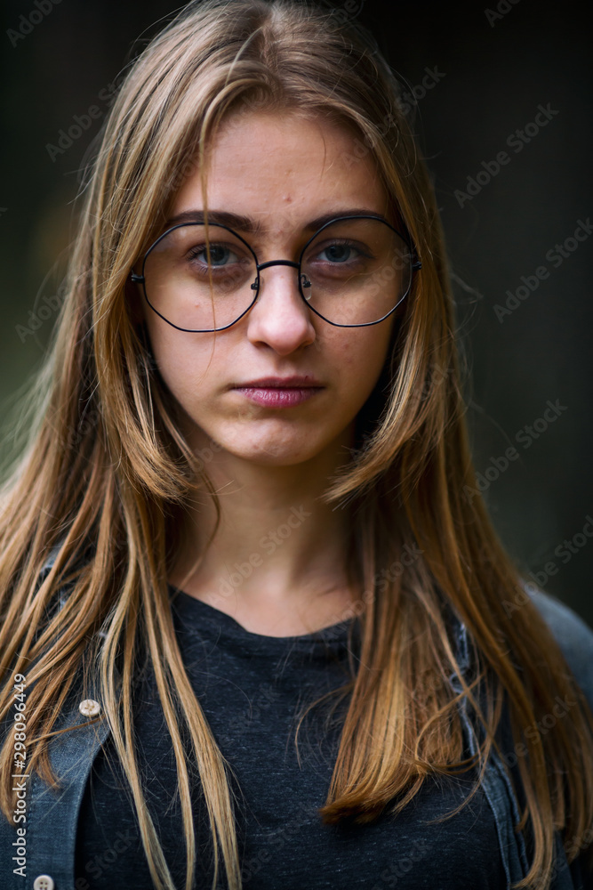 Teenager. Young beautiful white caucasian teenage girl in casual clothes and glasses on the street in the dark forest in the autumn evening. Close up. Teenager. Young beautiful white caucasian teenage girl in casual clothes and glasses on the street in the dark forest in the autumn evening. Close up.