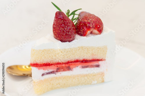 A piece of strawberry cake with cream and strawberry jam layers and topping with two fresh strawberry.