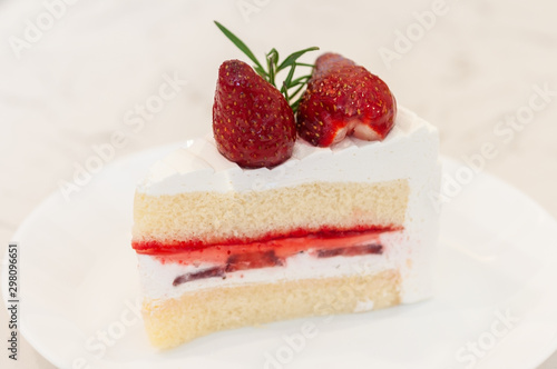A piece of strawberry cake with cream and strawberry jam layers and topping with two fresh strawberry.