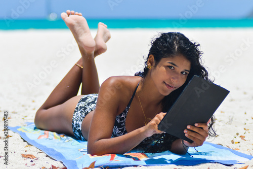 carefree woman uses touchpad tablet technology on the beach with internet vacation