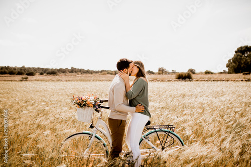 Sincere lovers posing by bicycle on rye field