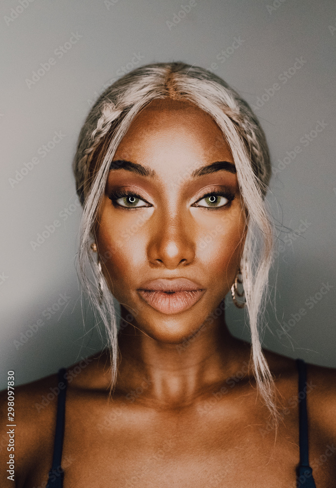 Portrait of adult African American female with blond hair wearing blue and looking at camera Portrait of adult African American female with blond hair wearing blue and looking at camera
