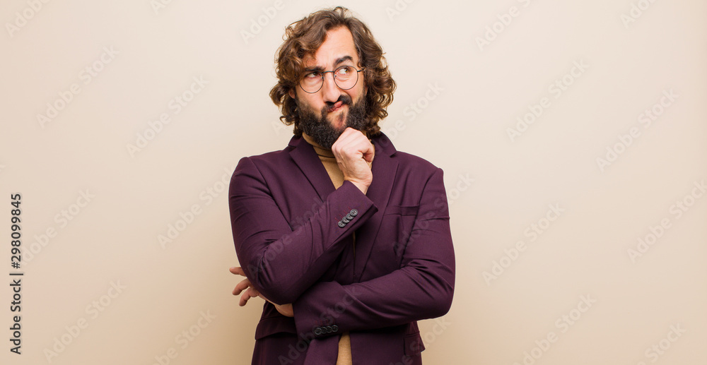 Fotografie young bearded crazy man thinking, feeling doubtful and confused, with different