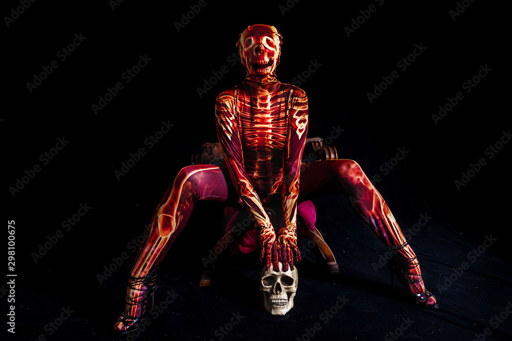 sensual woman dressed in a skeleton costume sitting on old chair