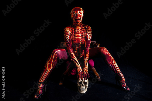 sensual woman dressed in a skeleton costume sitting on old chair