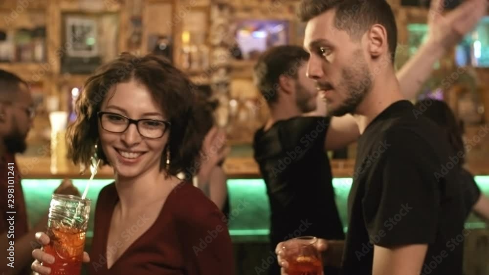 Portrait of cheerful young couple enjoying drinks and music at party at bar or nightclub and looking at camera Portrait of cheerful young couple enjoying drinks and music at party at bar or nightclub and looking at camera