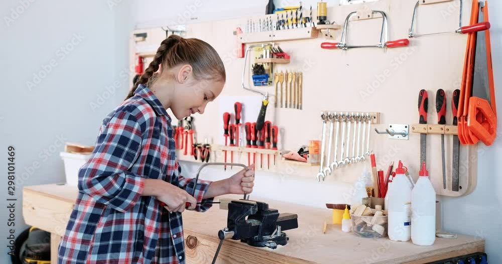 Preteen girl using the fretsaw in the wood workshop Preteen girl using the fretsaw in the wood workshop