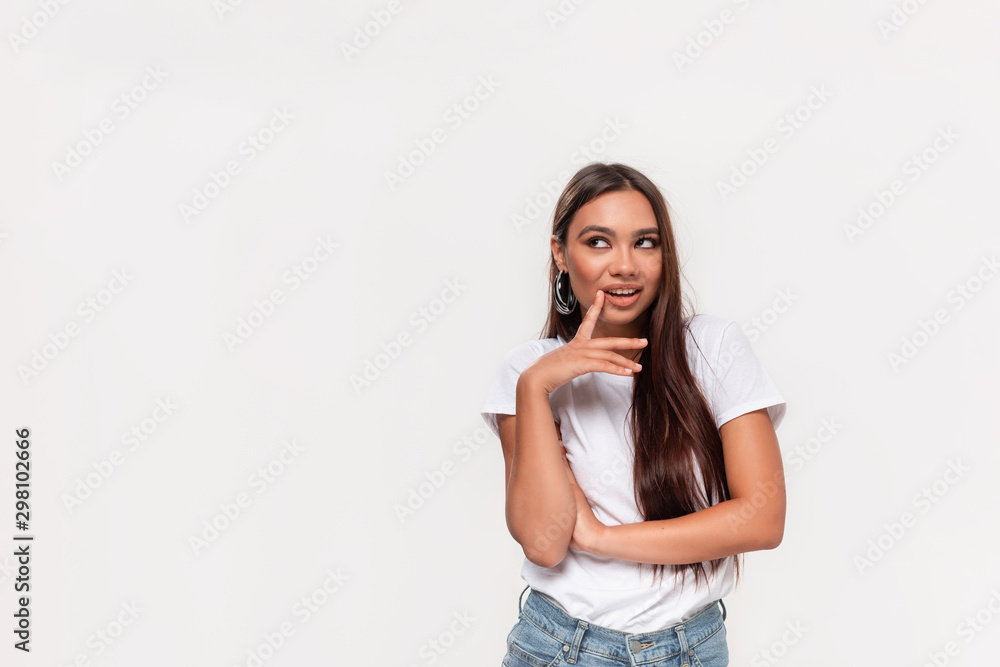 Pretty african-american teenager in a white tee and blue jeans thinking smiling isolated over white background. Copy space for advertising. Pretty african-american teenager in a white tee and blue jeans thinking smiling isolated over white background. Copy space for advertising.