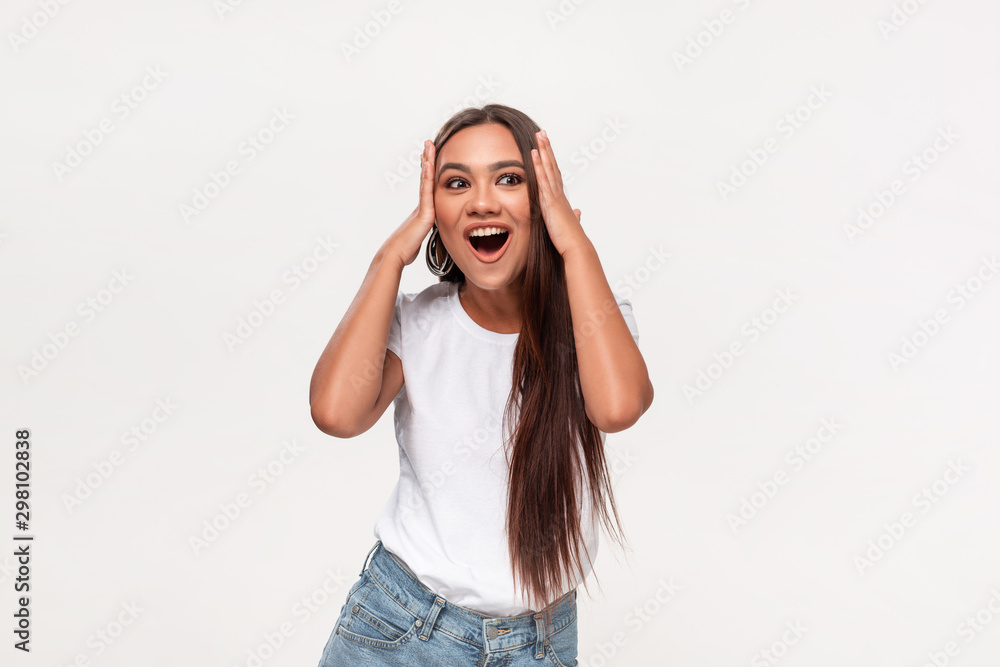 Excited african-american teenager in a white t-shirt and blue jeans dancing isolated over white background. Concept of success Excited african-american teenager in a white t-shirt and blue jeans dancing isolated over white background. Concept of success