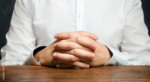 A man sits at the table with folded arms. Ready to listen to news. Serious talk. Calmly. Communication and body expressions. job interview. Self confidence. Understand the essence of the problem.