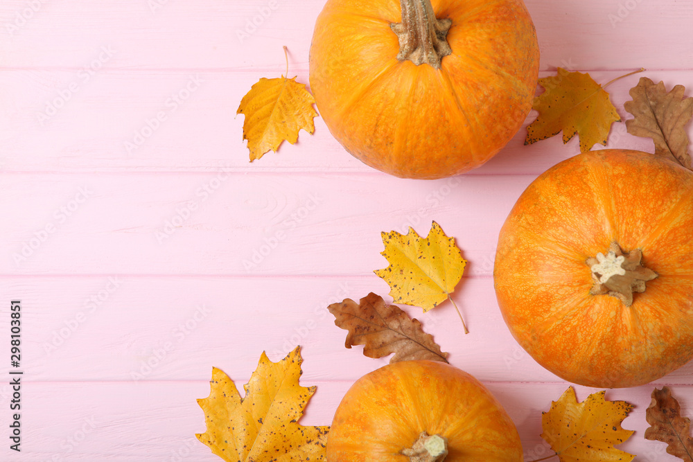 Autumn background with leaves and pumpkins on a colored background top view. Thanksgiving concept.