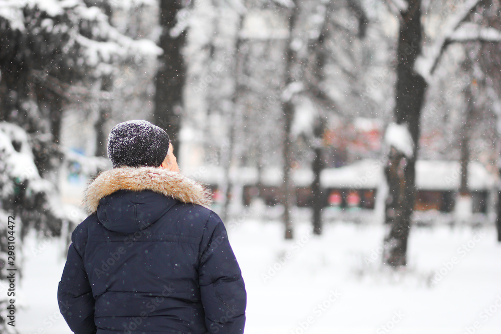 Back of man looking up in snowy park in winter Back of man looking up in snowy park in winter
