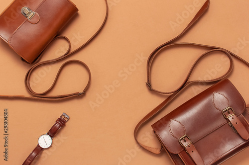 Brown leather women bag, stylish wristwatch on brown beige background top view flat lay copy space. Fashionable women's accessories. Sales Fashion Concept. Stylish Lady Clothes. Luxury Leather Bag