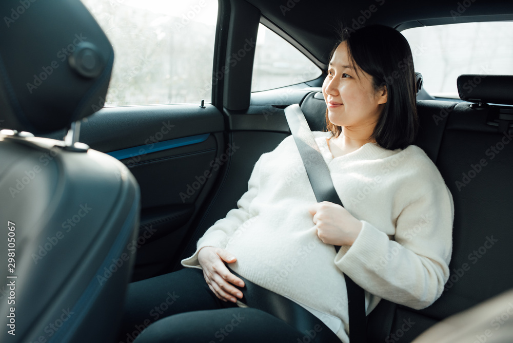 Pregnant woman fastening safety belt in her car Pregnant woman fastening safety belt in her car