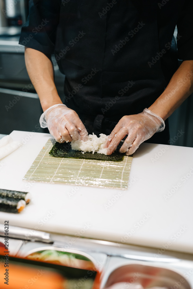 Crop cook making sushi with rolling mat Crop cook making sushi with rolling mat