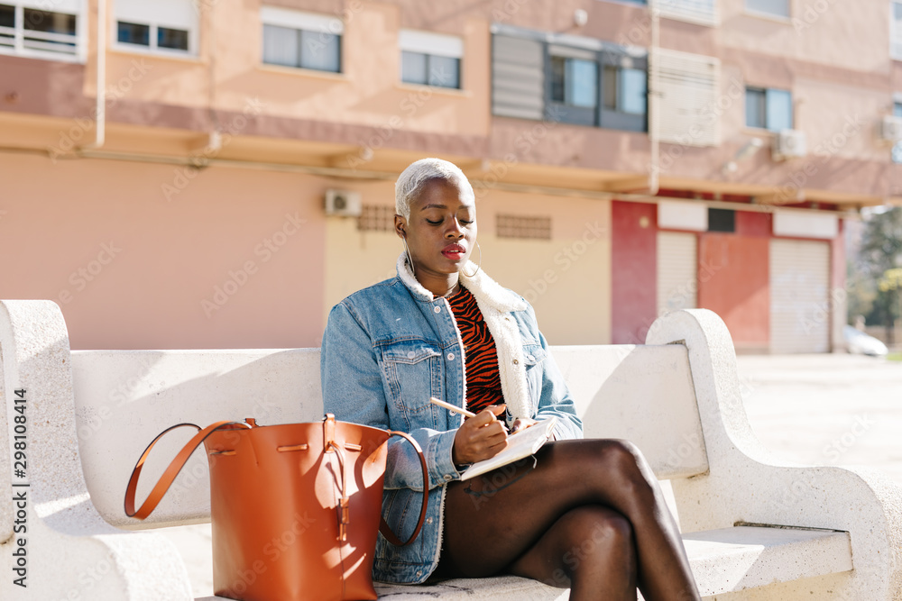 © Javier Díez/Stocksy - Black lady sitting on bench on street © Javier Díez/Stocksy - Black lady sitting on bench on street