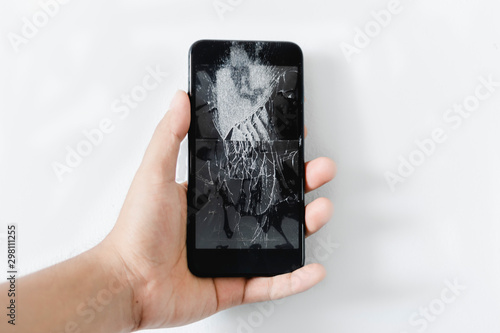 Man hand holding mobile phone with broken screen