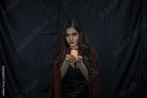 Young Asian woman in costume witch on black cloth background.