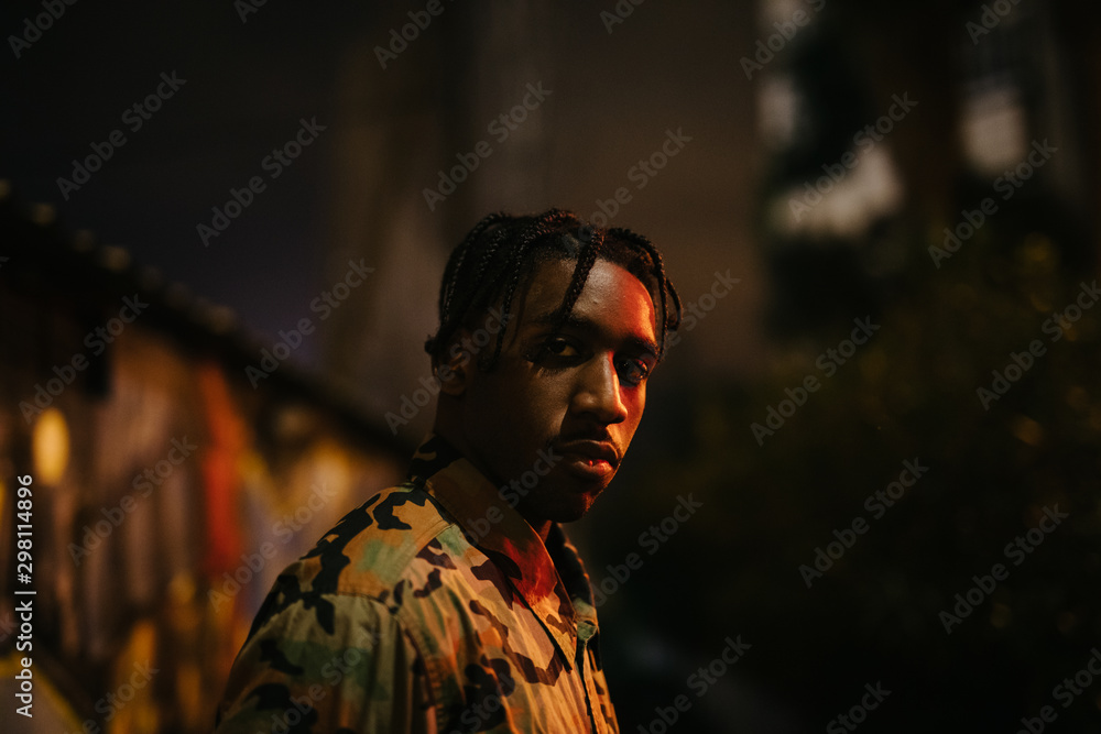 Black man standing near graffiti wall at night Black man standing near graffiti wall at night