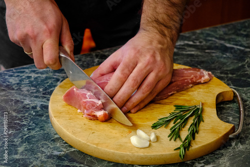Male chef cuts fresh meat on a wooden board