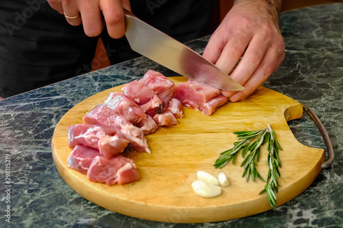 Male chef cuts fresh meat on a wooden board