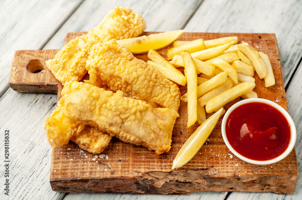 Naklejka premium fish and chips with french fries, on wooden background