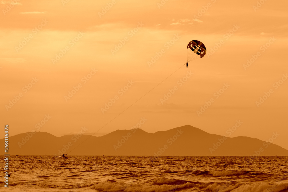 Parasailing in the evening sky near the coast of Vietnam. Orange color toned Parasailing in the evening sky near the coast of Vietnam. Orange color toned