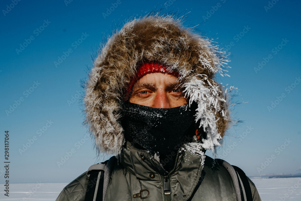 Man in hood and scarf on face with hoarfrost Man in hood and scarf on face with hoarfrost