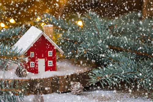 Miniature Christmas wooden house on the snow over blurred snowflakes background, toned