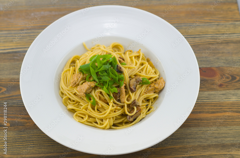 Creamy spaghetti with chicken and mixed mushrooms. Sprinkled with spring onions cut into rings. Freshly prepared and served as a healthy and fast meal of Italian cuisine.