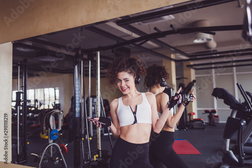 happy woman in headphones listening to music in the gym
