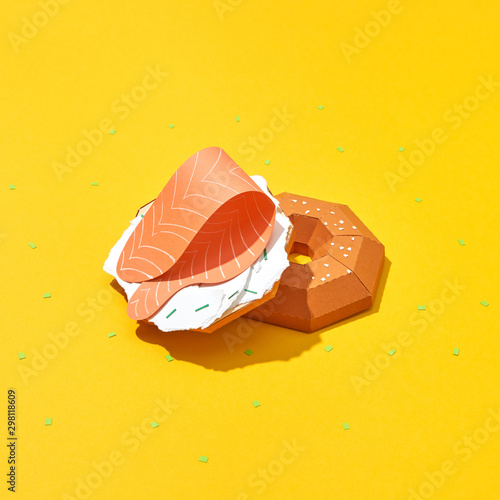 Handmade crafting bun with pieces of paper cheese and a piece of salmon on a yellow background with copy space. Snack. Flat lay photo