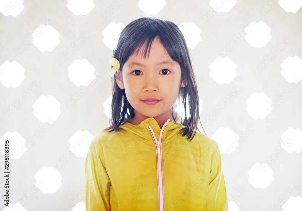 Cute Asian little girl wearing plumeria flowers in front of quaint windows. Travel in Hanoi Cute Asian little girl wearing plumeria flowers in front of quaint windows. Travel in Hanoi